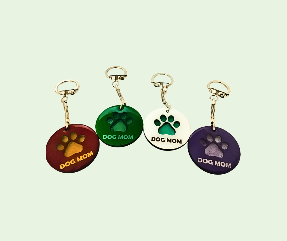 'Dog Mom' keychains with paw prints on a light green background