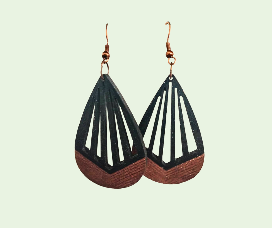 Pair of geometric earrings with black, white, and brown design on a light green background