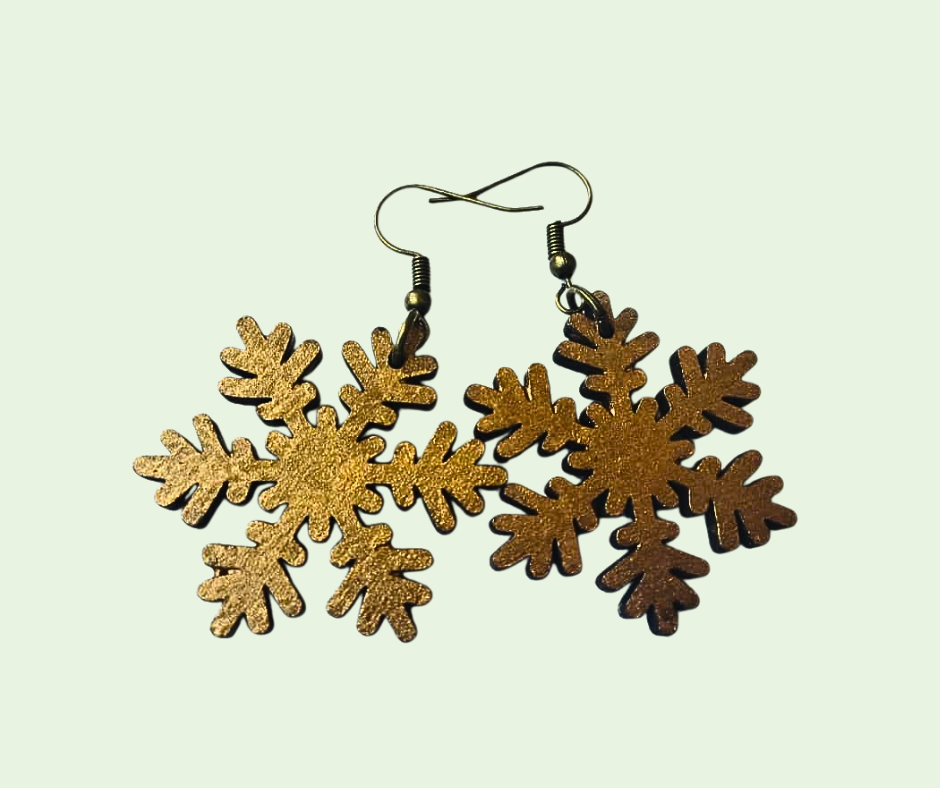 Gold snowflake earrings on a light green background